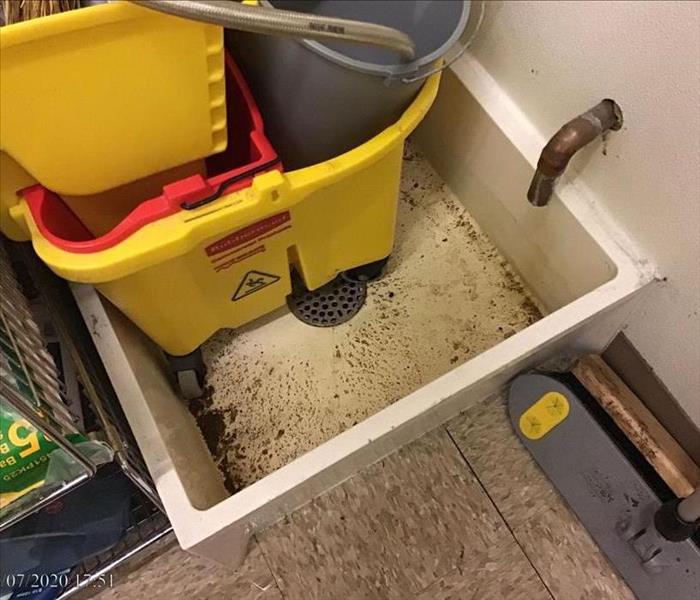 A clogged mop sink before cleaning
